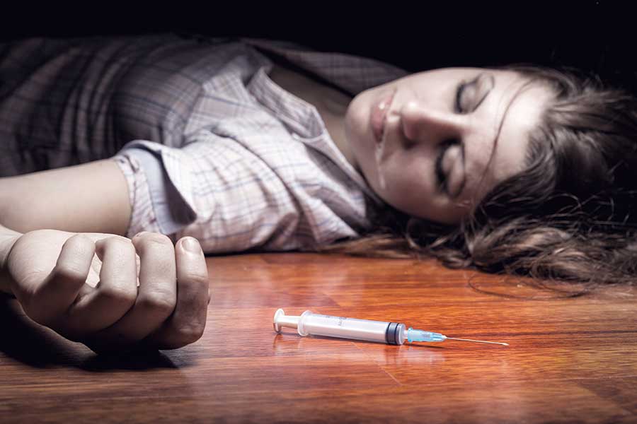 woman laying on the floor next to needle suffers heroin overdose