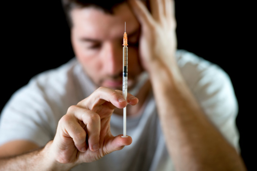 Heroin Addiction Man at risk for 5 signs of heroin use overdose staring at needle